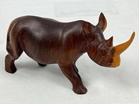 Left side view of carved wood rhinoceros with horn and body details visible