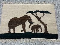 Full view of handwoven rug showing elephant scene, fringe visible