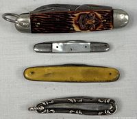 Group of four closed pocket knives arranged horizontally