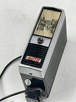 Oblique front view showing flash lens, AUTO sensor grill and attached PC cord