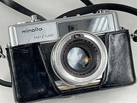 Front view of Minolta Hi-Matic 9 camera in leather case, shows Easy Flash branding, lens, strap