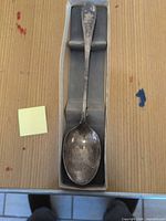 Full view of serving spoon in box showing overall length and tarnish