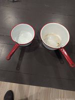 Both enamel saucepans side by side showing size difference and condition