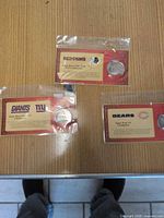 Three packaged NFL Super Bowl champion coins on table
