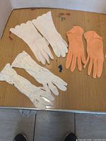 All three glove pairs laid out: white scalloped, white lace, peach leather