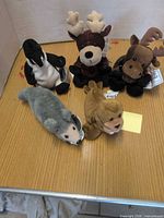 Group shot of five Coca-Cola bean bag plush animals on table