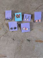 All six pairs of earrings displayed on purple or blue cards