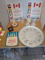 Entire lot displayed on table including tray, coasters, glass, booklets, book and small dishes