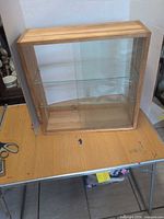 Full view of cabinet front showing wood frame, glass doors, two glass shelves