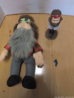 Plush doll lying and bobblehead standing on tabletop