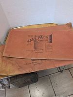 Two folded Safe-Pack garment bags showing printed label and size