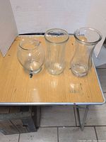 Three clear glass vases displayed on table