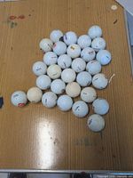 Group of 30 assorted white golf balls on table