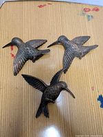 All three bronze-tone plastic hummingbird wall hangers on tabletop