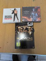 Front view of three media cases: King of Pop CD, HIStory CD, The Jacksons A Family Dynasty DVD