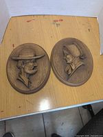 Both carved wood plaques side by side on table