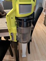 Upper section of Ryobi stick vacuum showing clear dust canister and yellow housing