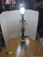 Full view of lit brass and crystal table lamp against backdrop