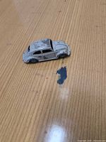 Left side view of grey Dinky Toys Volkswagen Beetle missing wheels