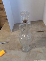 Full view of glass decanter with stopper and handles