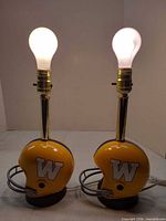 Front view of both helmet lamps with bulbs lit showing logos, colors, faceguards