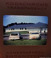 Slide showing two sedans parked in front of ranch house