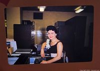Workplace portrait slide of woman seated at desk with typewriter
