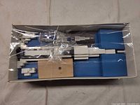 Overall view of box with plastic parts, wood stand, blue inserts