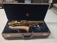 Saxophone body and detached neck inside blue-lined hard case