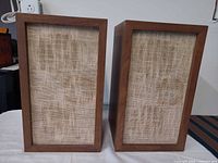 Front view pair of KLH Model Fifteen speakers showing wood veneer cabinets and beige woven grilles