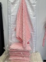 Stack of packaged pink towels with one towel draped to show size and texture