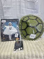 Overall lot showing ghost costume package, plush turtle shell, skeleton gloves