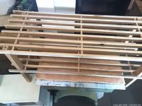 Full view of wooden folding shoe rack on table