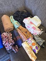 Assorted rolled and folded scarves laid on couch