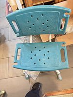 Top view of turquoise shower chair showing perforated seat and back with handholds