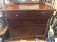 Front view of mahogany dresser showing five drawers and carved side columns