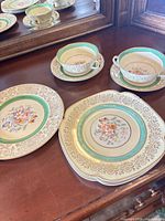 Group view of soup bowls with saucers, salad plates, serving plate on dresser