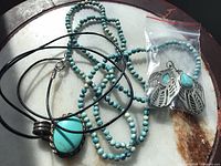 Overview of all three jewelry pieces: beaded necklace, cord pendant necklace, bagged dangle earrings