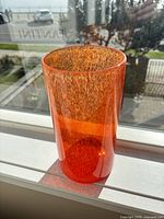 Orange glass cylinder vase on windowsill