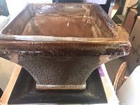 Angled view of square glazed planter on base