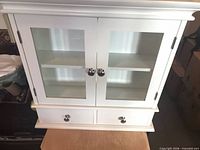 front view of white cabinet showing glass doors and two drawers