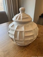 Front angled view of white geometric ceramic jar with lid