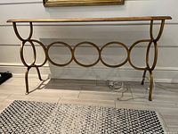 Front view of gold metal console table with five ring motif and mirrored top