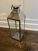 front view of rectangular polished metal hurricane lantern with glass sides
