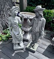 Courting couple statues standing beside urn planter