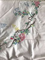 Close-up of embroidered floral design on white linen runner