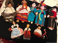 Group shot of ten ethnic dolls laid on black fabric
