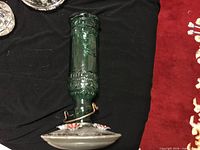 Green glass hummingbird feeder lying on side