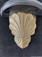Front view showing gold-tone metal shell motif corbel and wood shelf