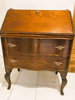 Front view of tiger oak drop-front desk with drawers and cabriole legs